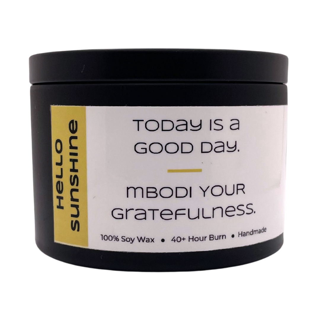 Mbodi 6 oz soy candle ‘Hello Sunshine’ in metal tin with bright yellow label designed for a bright, uplifting, and warm atmosphere