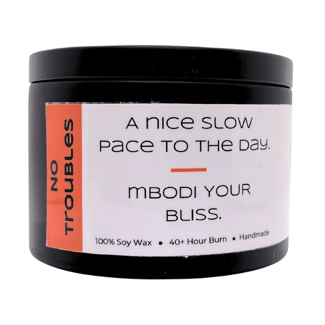 Mbodi 6 oz soy candle ‘No Troubles’ in metal tin with orange label designed for a calm, stress free atmosphere