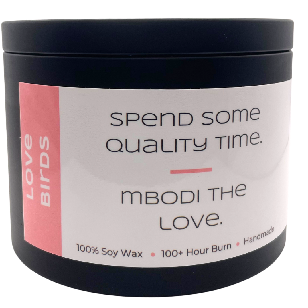 Mbodi 15 oz soy candle ‘Love Birds’ in metal tin with bright pink label designed for a warm, romantic atmosphere and connection